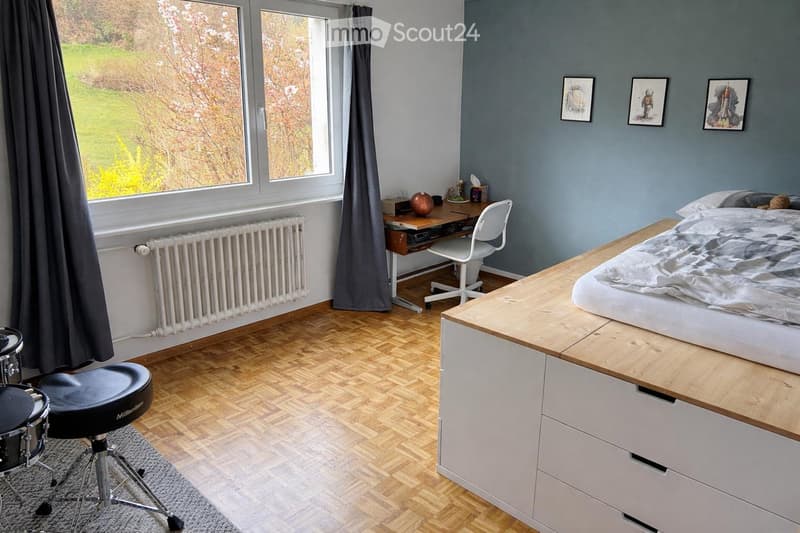 bedroom with bed, desk, chair, radiator, window, curtains, drum set, rug