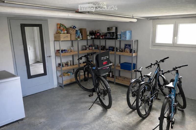 A room with a door, mirror, shelves, bicycles, and a refrigerator