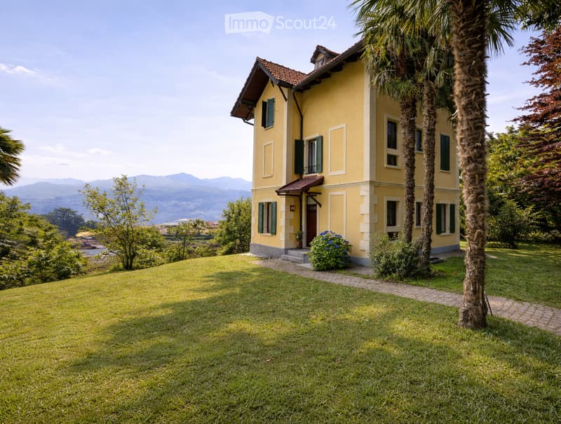 2 story house, yellow exterior, red roof, large windows, surrounded by greenery, mountain view