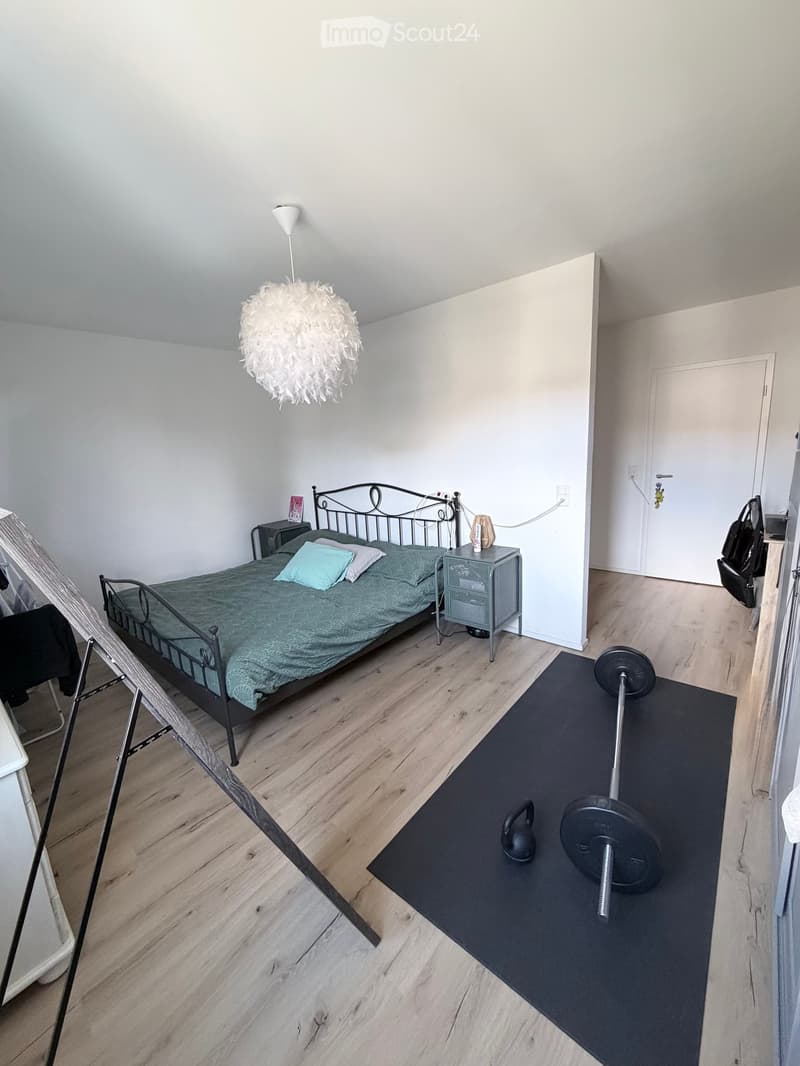 bedroom with bed, nightstands, lamp, exercise equipment, wooden floor