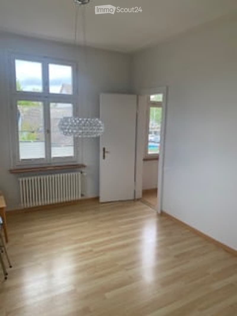 empty room, wooden floor, white walls, large window, radiator, chandelier