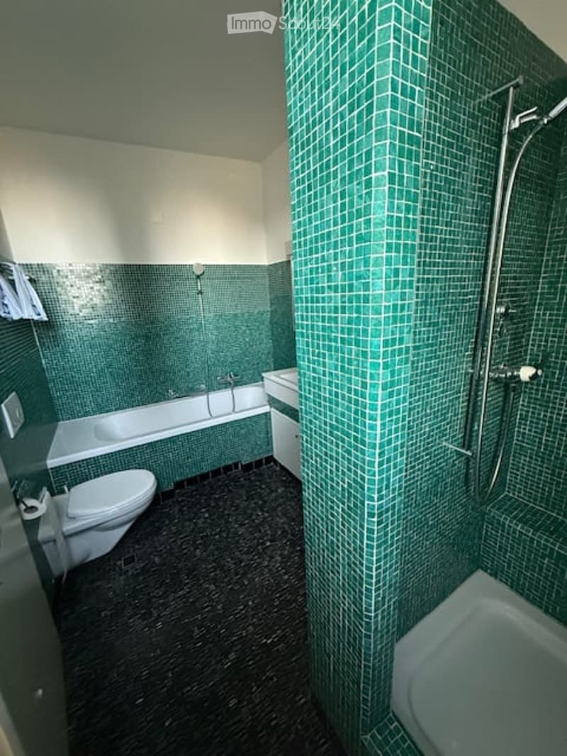 Bathroom with green tiles, bathtub, shower, toilet, sink