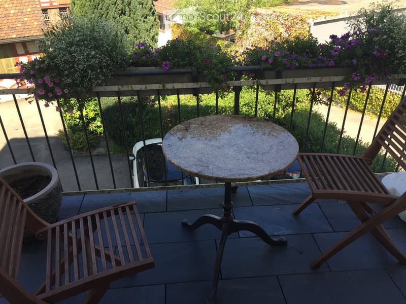 Balcony with table and chairs, railing, plants, and a view of the street
