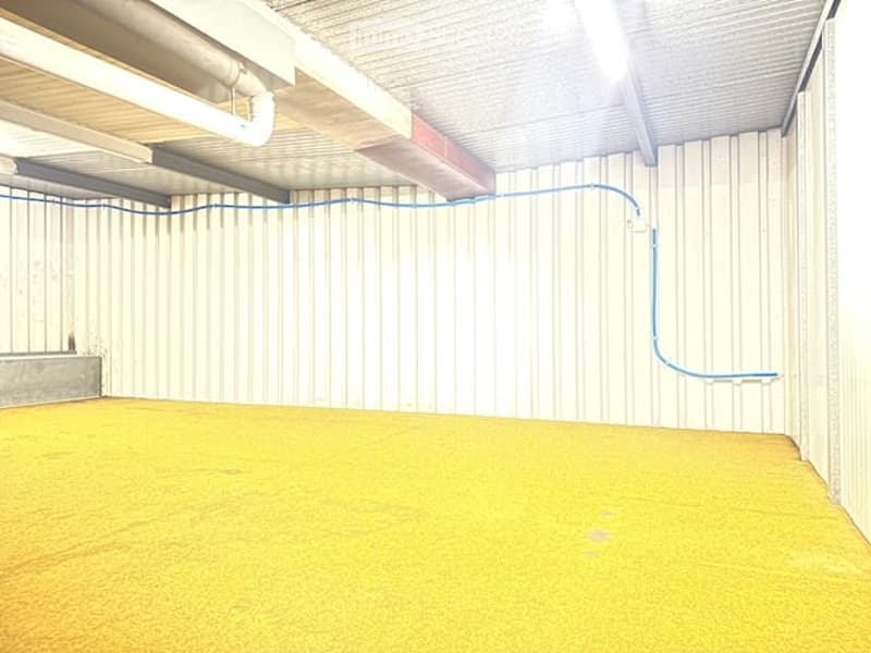 Empty room with yellow floor, white walls, metal ceiling, and blue pipe