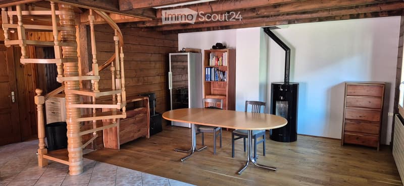 wooden spiral staircase, round table, chairs, wooden shelves, books, fireplace, radiator
