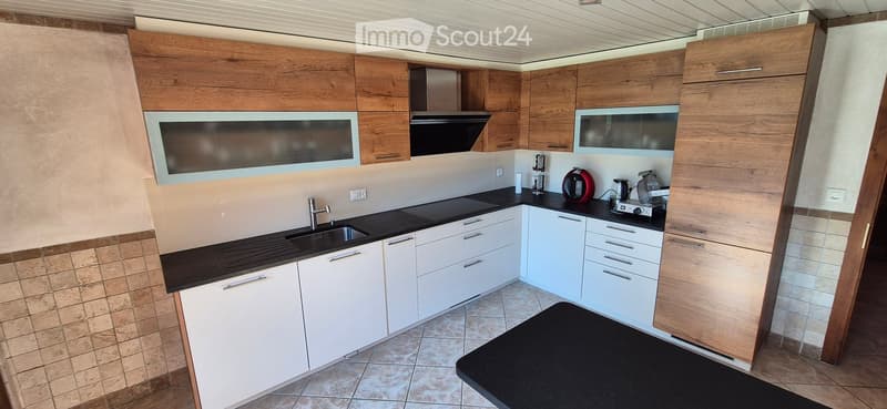 modern kitchen with wooden cabinets, black countertops, white tiles, stainless steel sink, gas stove, and various kitchen appliances