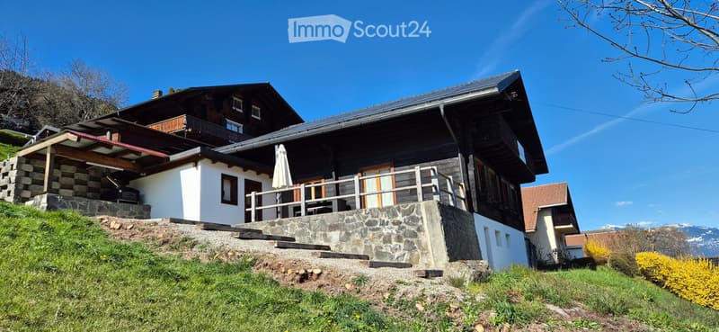 2 story house, raised ground floor, wooden exterior, balcony, solar panels on roof