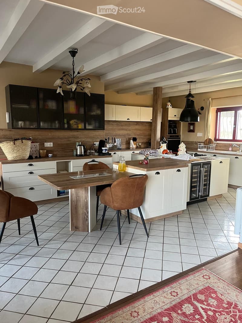 modern kitchen with wooden island, white cabinets, tiled floor, chandelier, dining table, chairs, kitchen appliances, window