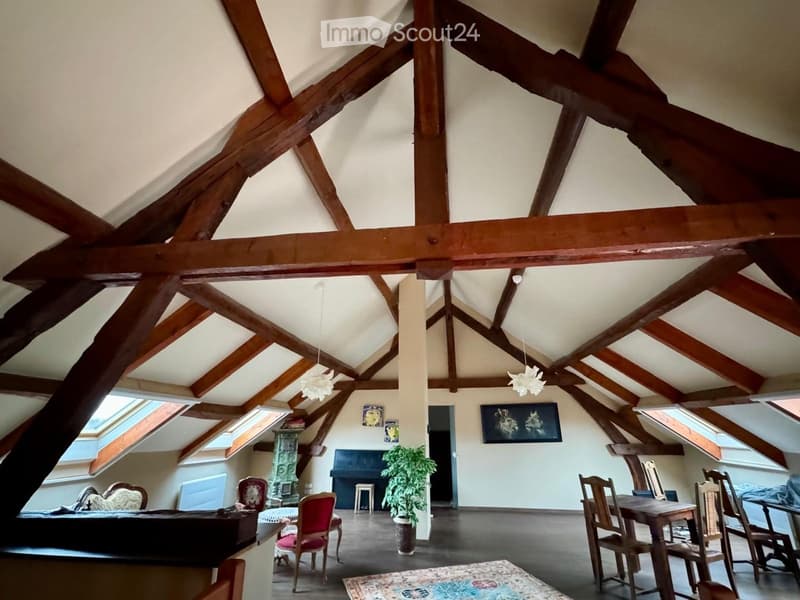 attic room with wooden beams, piano, wooden table and chairs, rug, potted plant, skylights