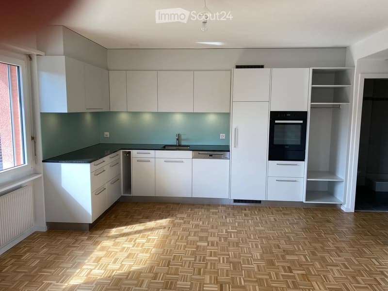modern kitchen with white cabinets, black countertops, integrated dishwasher, built-in oven, and a window