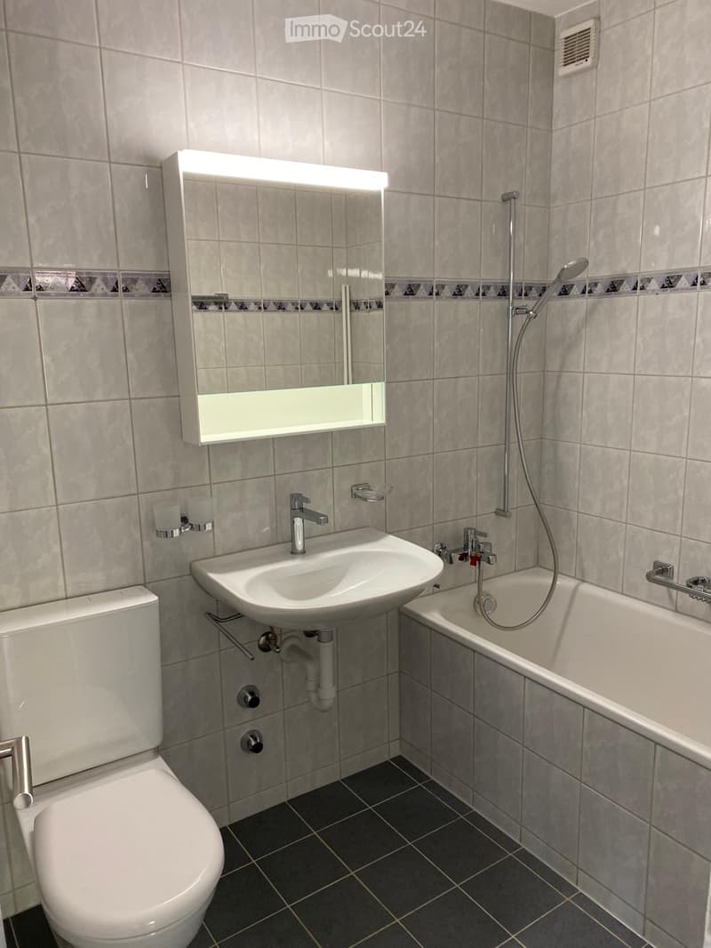 Bathroom with white tiles, white toilet, white sink, white bathtub, mirror, shower head, and faucets