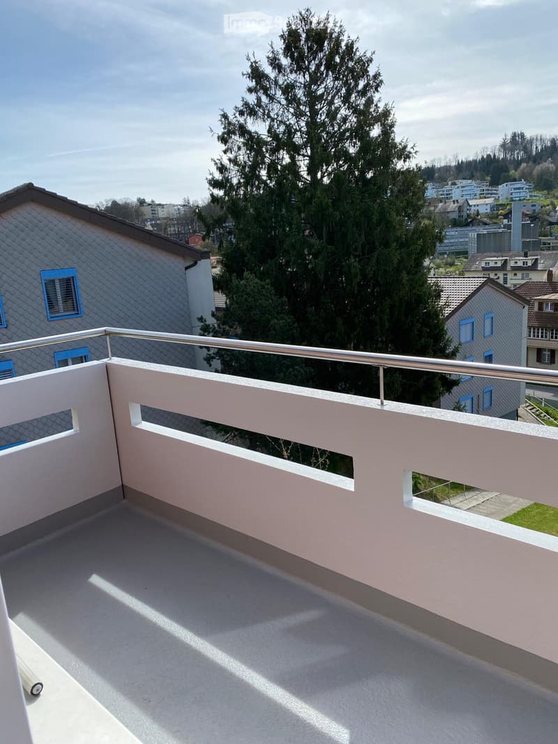 Balcony with railings, view of a tree and buildings