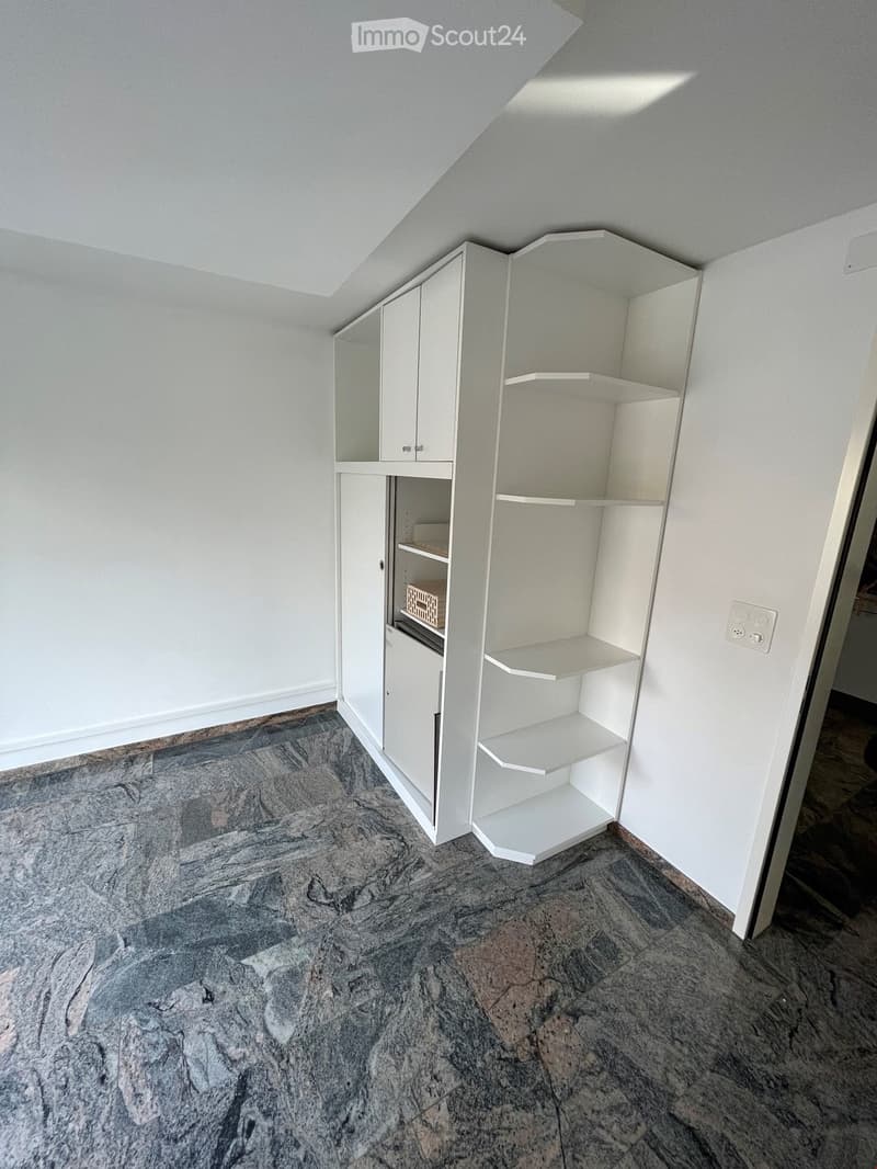 Empty room with white walls, white built-in cabinet, and granite floor