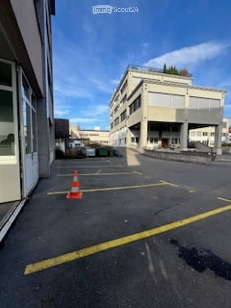 Empty parking lot with yellow lines, building in the background