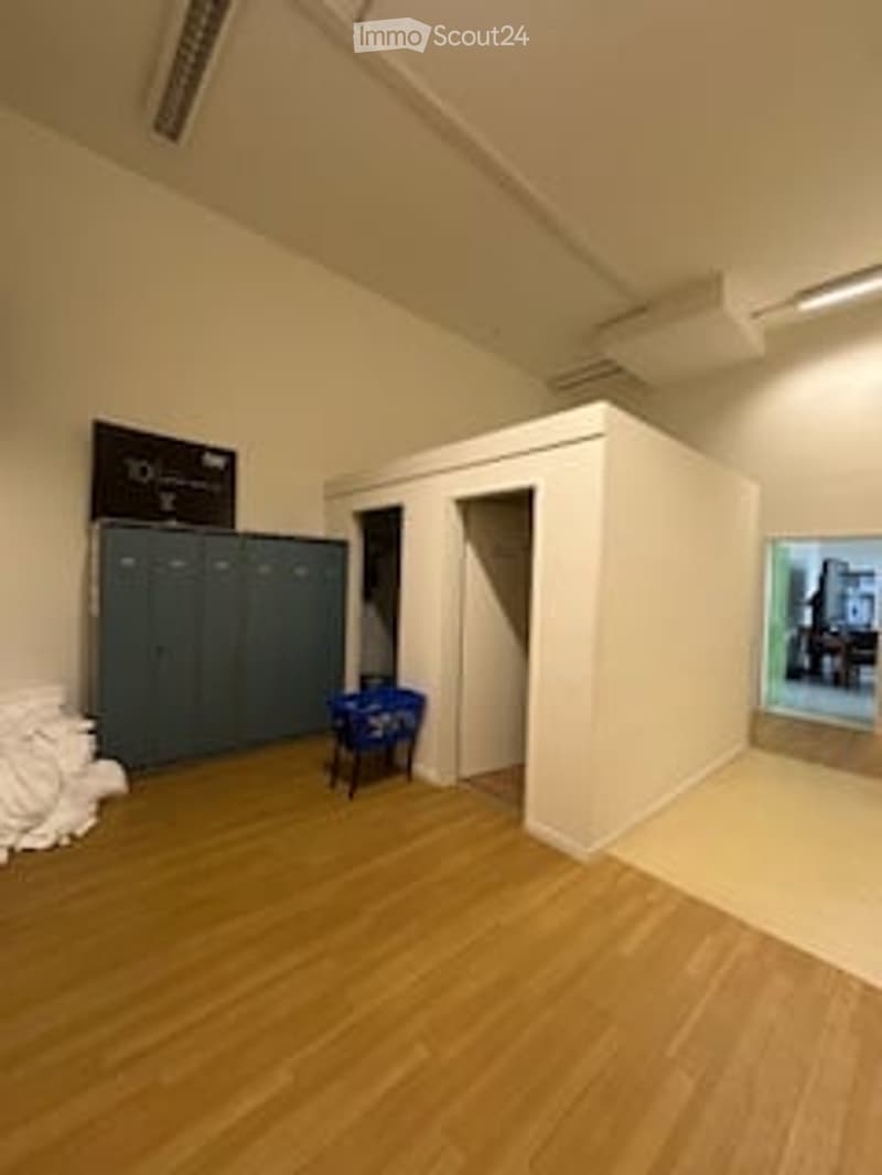empty room, wooden floor, white walls, lockers, blue chair, black monitor