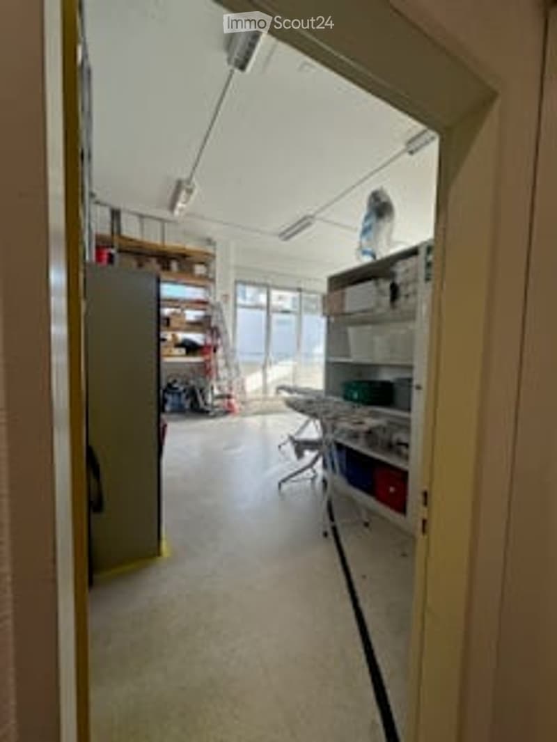 Empty room with white walls, white floor, shelves, ladder, table, boxes, and a window