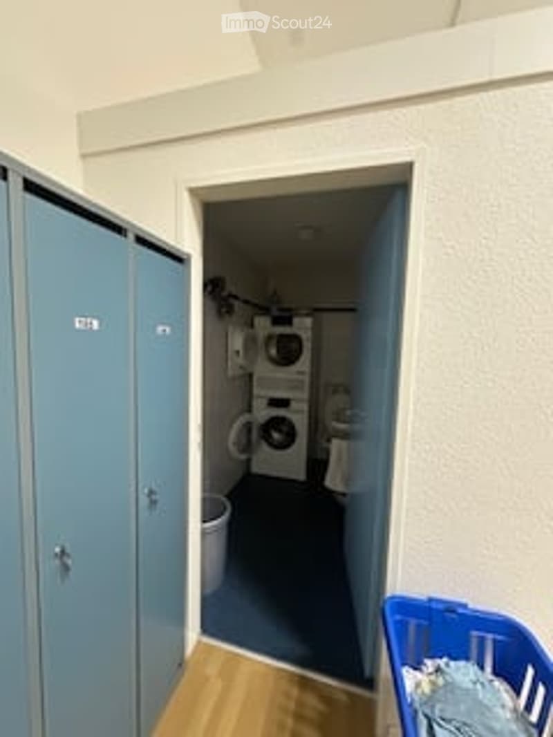 Laundry room with two washing machines, a dryer, a toilet, and a blue laundry basket.