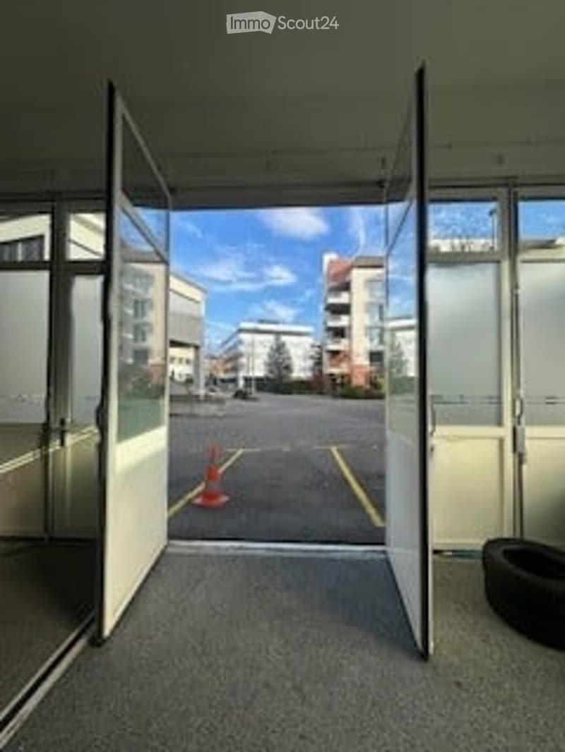 Open door leading to parking lot, glass walls, orange cone, tire