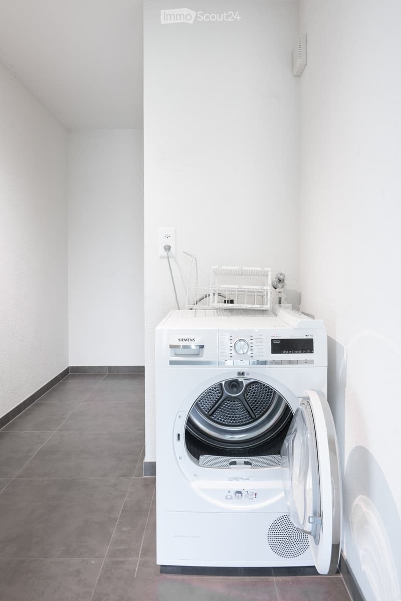 Bathroom. A modern bathroom with a white Siemens washing machine, tiled floor, and white walls.