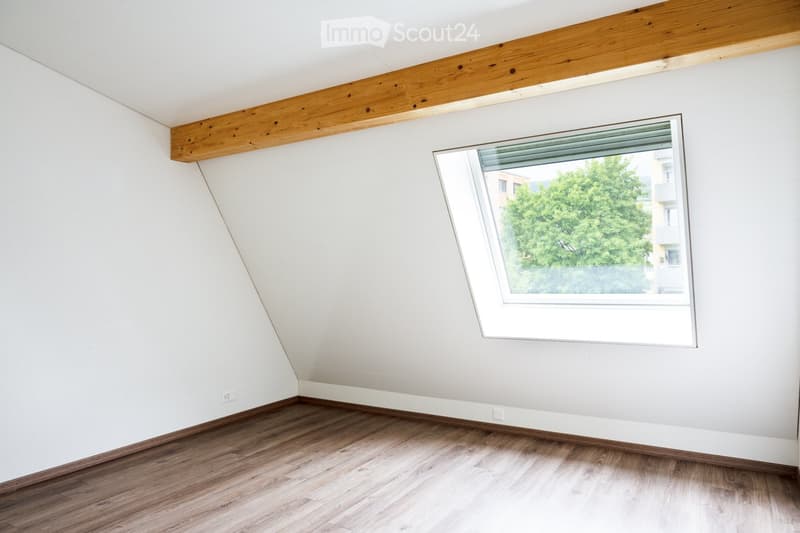 Unfurnished Room. Empty room with wooden flooring, white walls, and a large window with a view of greenery outside.