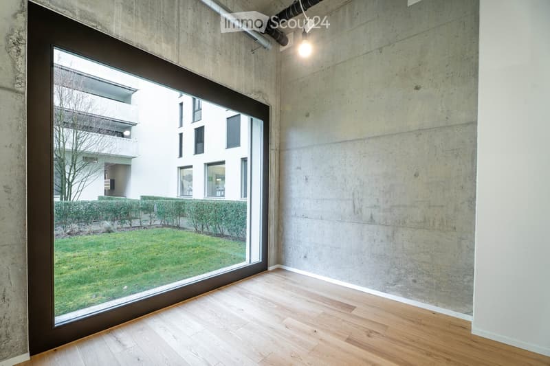 large window, hardwood floor, concrete wall, view of a grassy area