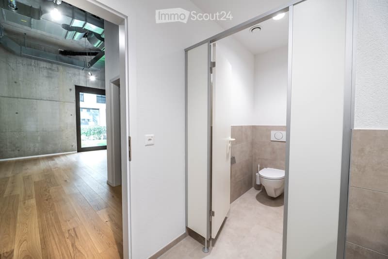 Modern bathroom with white walls, wooden floor, white toilet, and tiled walls.