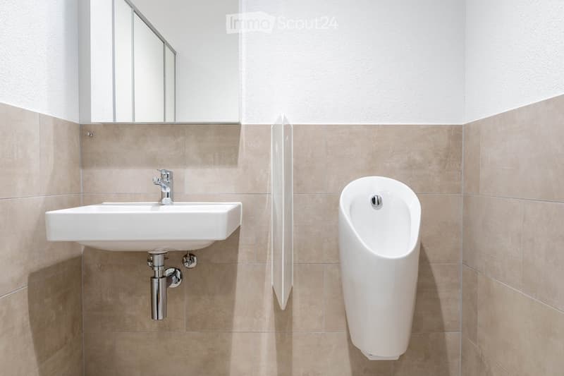 modern bathroom with white sink, silver faucet, mirror, urinal, beige tiles