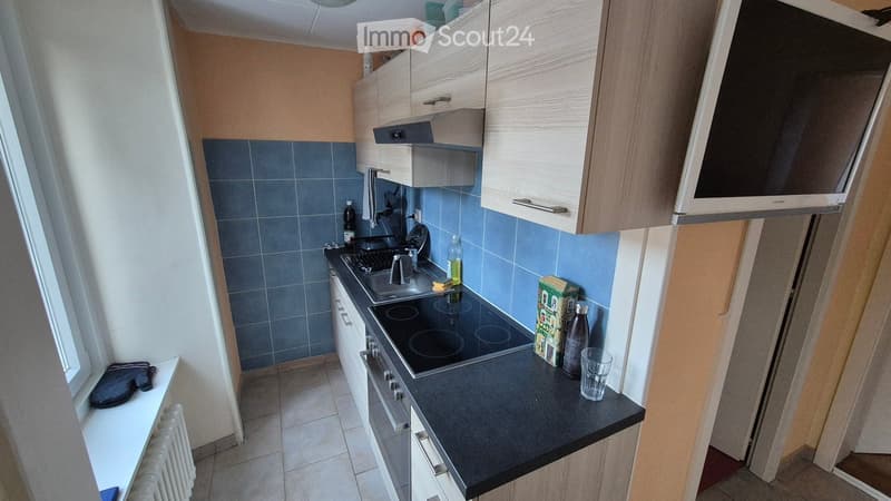 kitchen with blue tiles, black countertop, gas stove, sink, cabinets, radiator, window