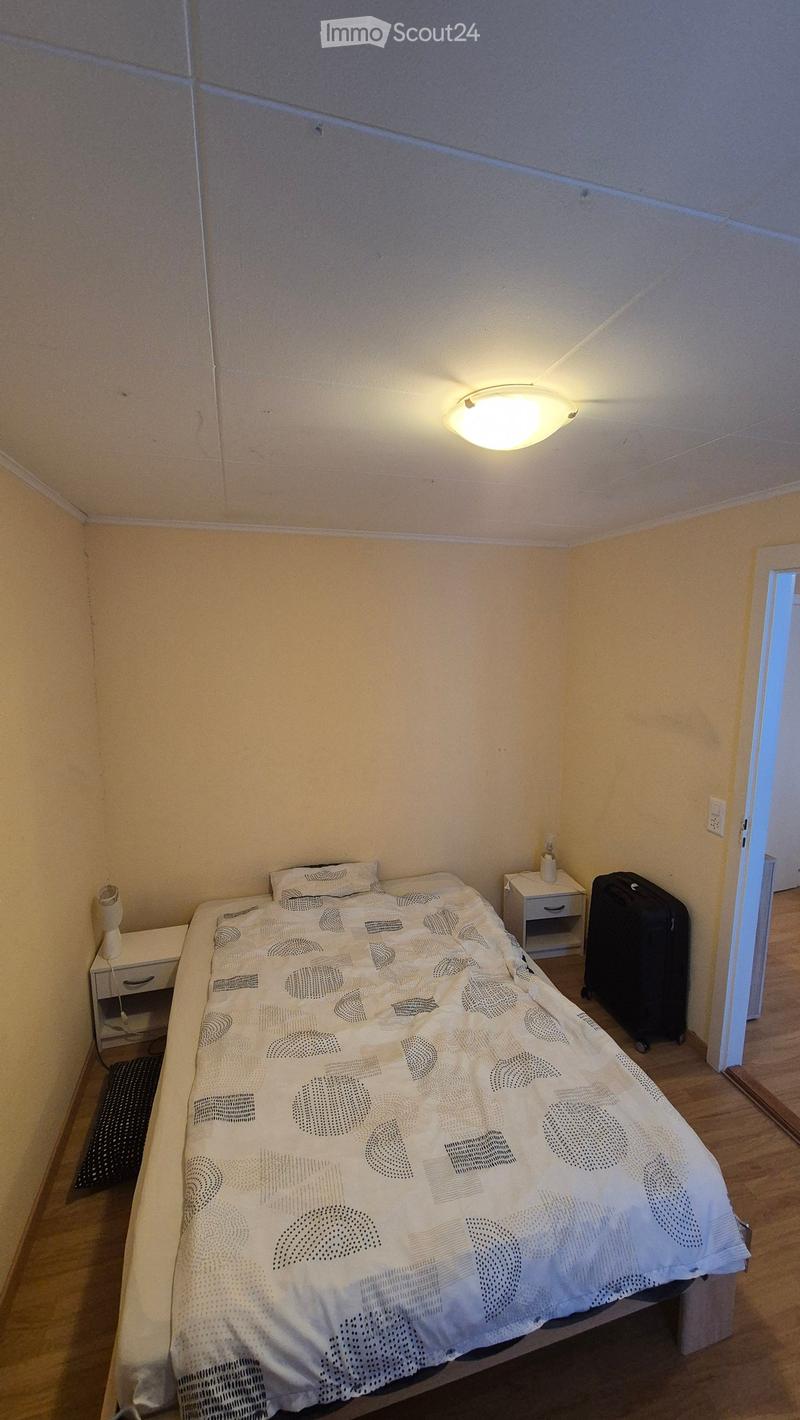A bedroom with a bed, two nightstands, a suitcase, and a lamp