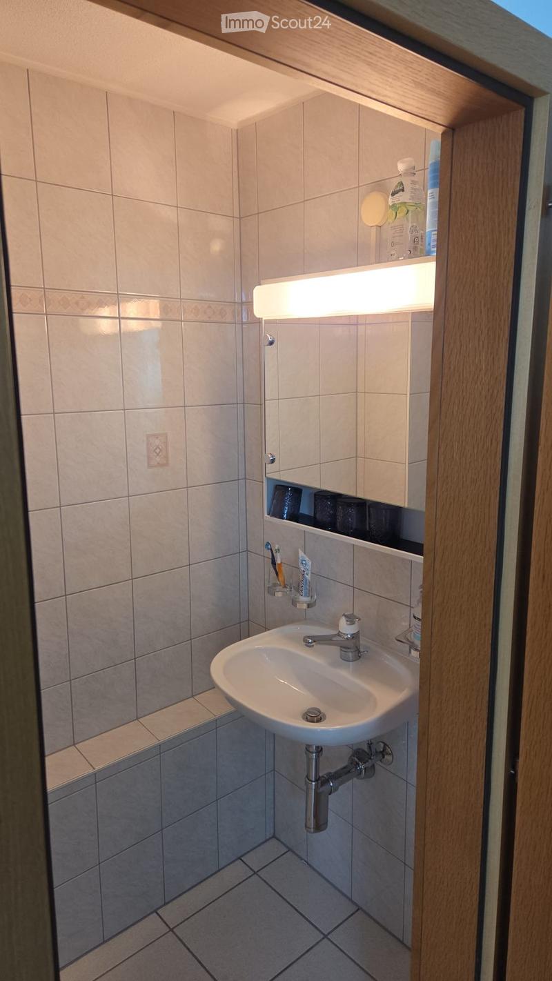 Bathroom with white tiles, sink, mirror, and a bench