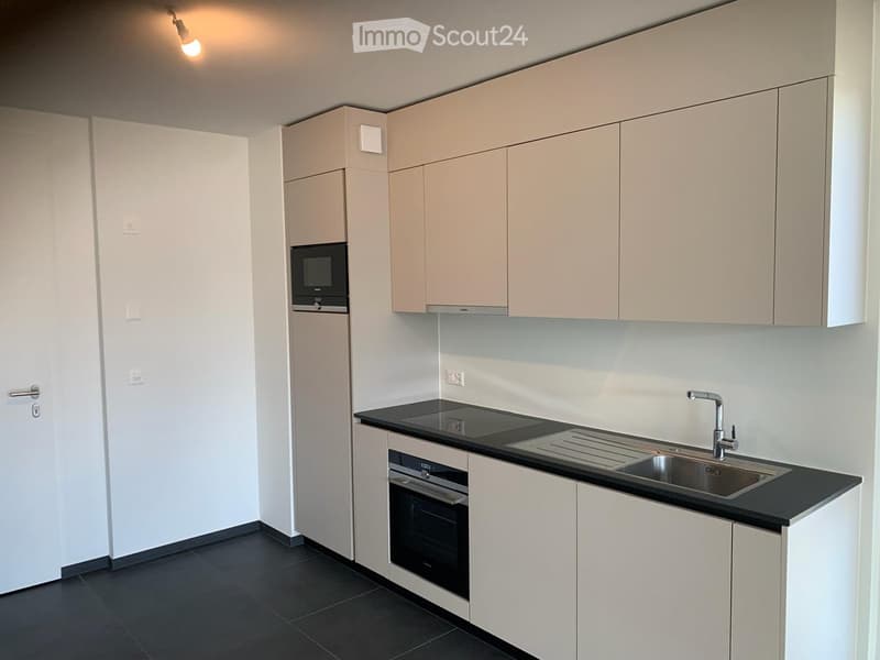modern kitchen with white cabinets, black countertops, integrated oven and microwave, stainless steel sink and faucet, tiled floor