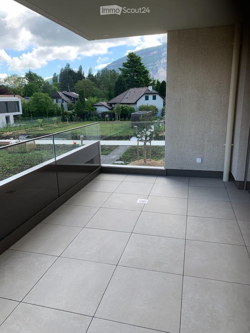 Balcony with glass railing, tiled floor, view of the garden and mountains