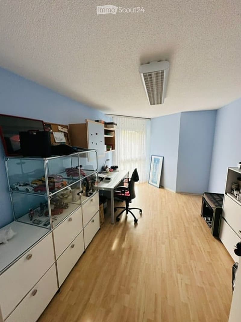 empty room, wooden floor, blue walls, desk, chair, cabinets, shelves, picture frame, ceiling light