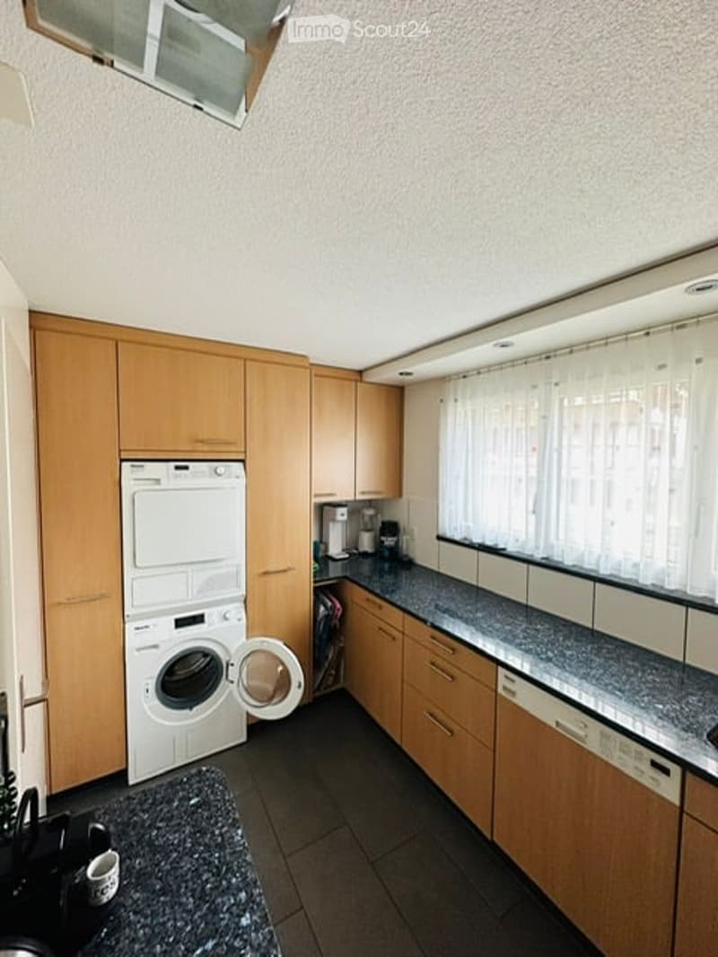 modern kitchen with wooden cabinets, granite countertops, white appliances, and a window with white curtains