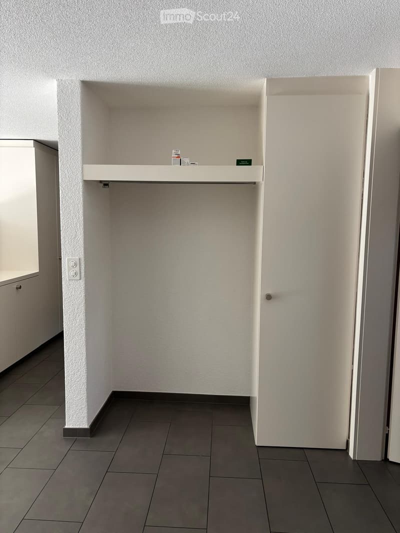 Empty room with white walls, tiled floor, and built-in shelving unit. No furniture or equipment present.