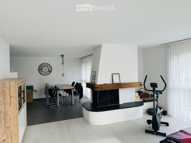 modern living room with fireplace, dining table, chairs, wooden cabinet, exercise bike, clock, picture frames, white curtains