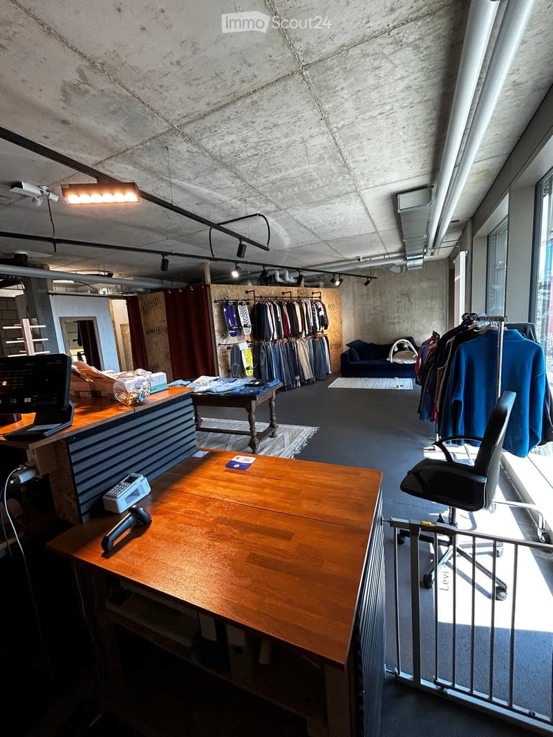 large room, clothing racks, desk, chair, monitor, telephone, rug, lights