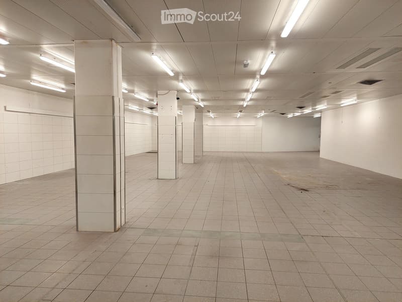 Empty room with tiled floor, white walls, and ceiling with multiple lights