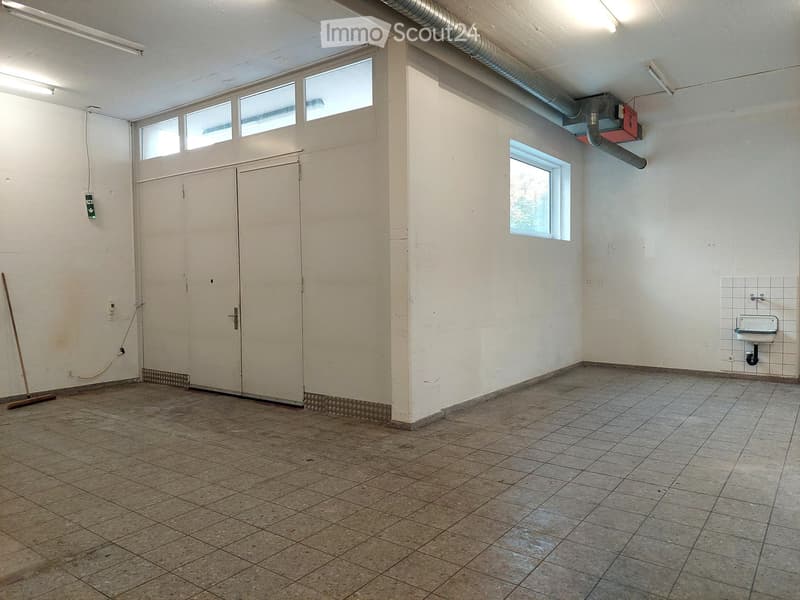 Empty room with tiled floor, white walls, two large doors, small window, sink, and pipe on the wall
