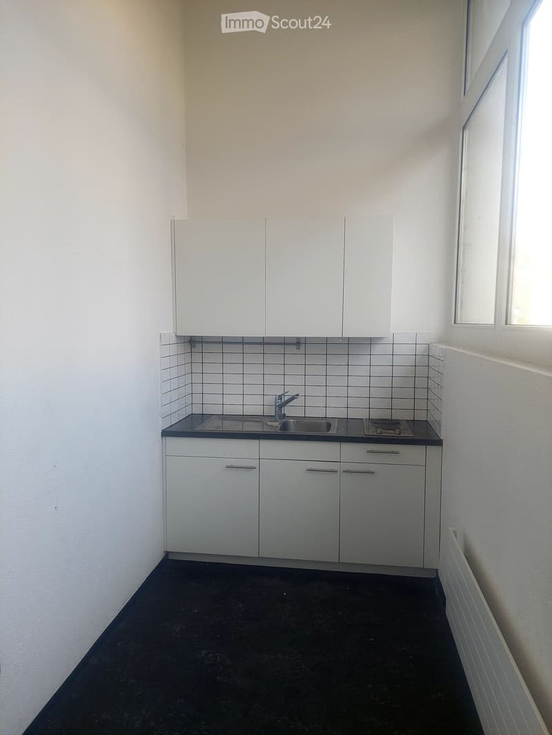 modern kitchen with white cabinets, black countertops, double sink, gas stove, white tiles, white walls, window