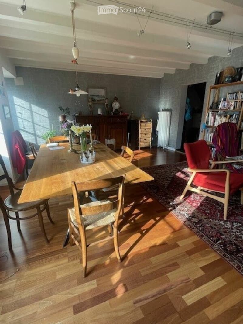 Dining room with wooden table, chairs, wooden floor, wooden cabinet, bookshelf, radiator, and decorative items