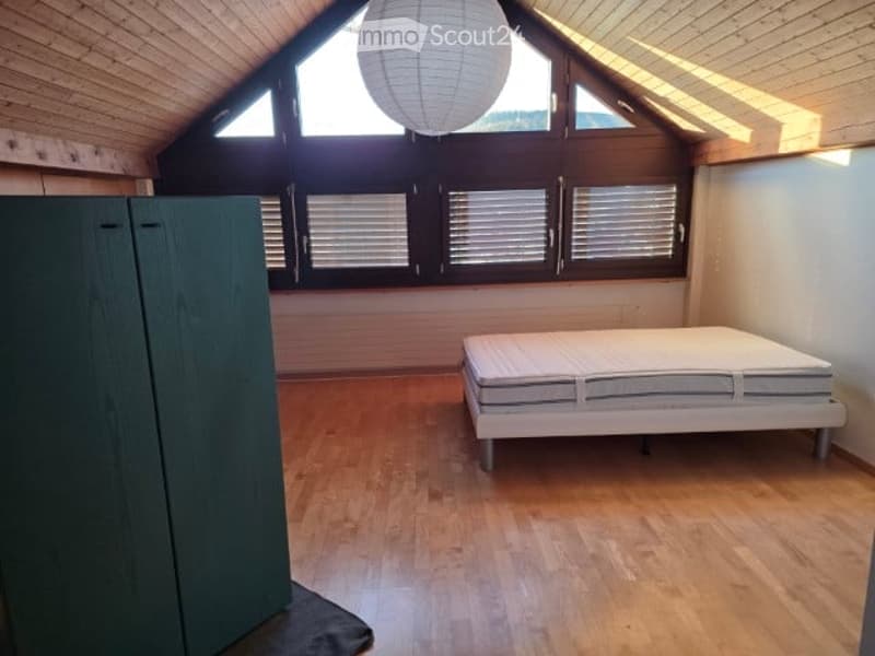 bedroom with wooden floor, white bed, green wardrobe, white lamp, large windows with shutters