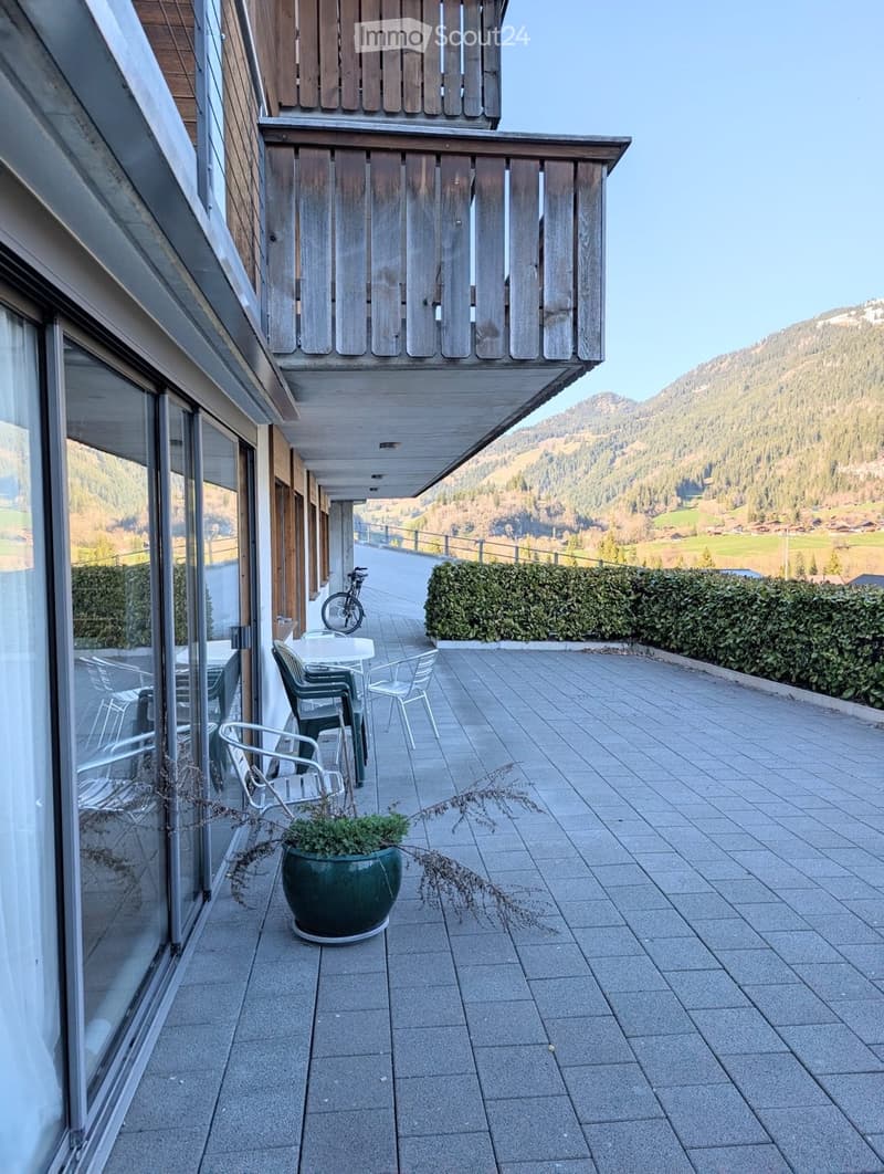 Balcony with wooden railing, tiled floor, outdoor seating, potted plant, bicycle, mountain view