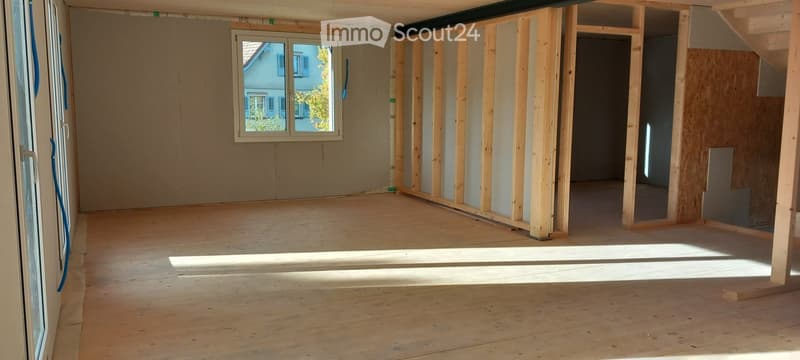Empty room with wooden floor, unfinished walls, and a window