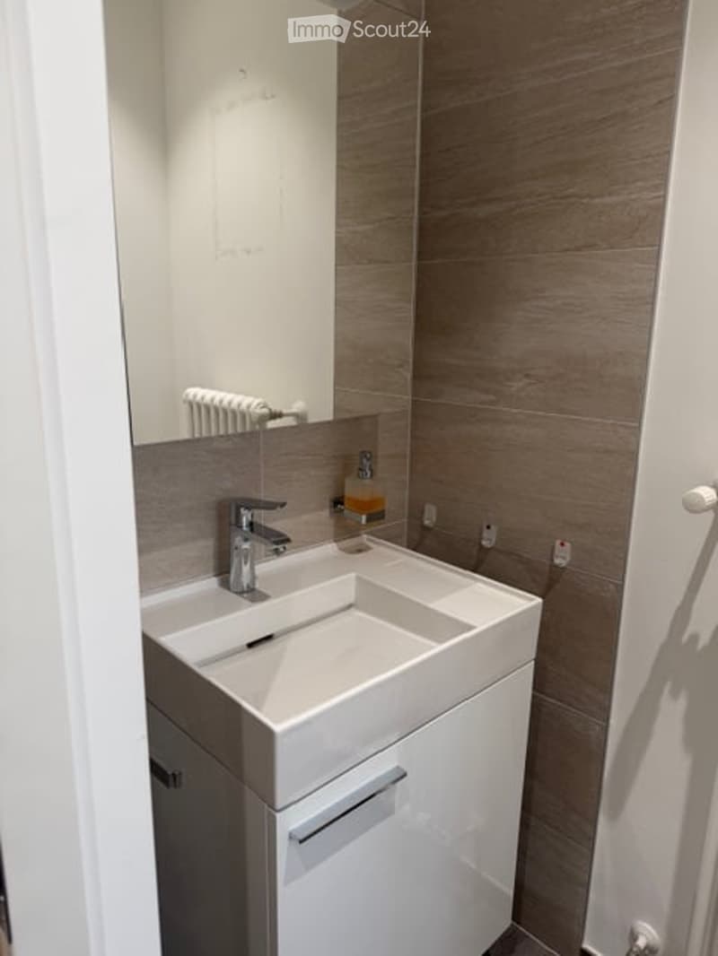 Bathroom with white sink, mirror, and tiled walls