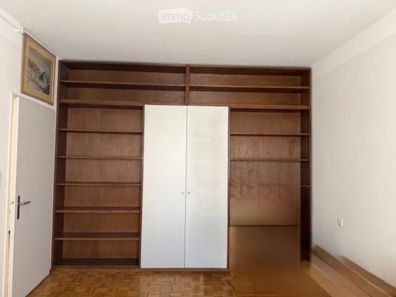empty room with wooden shelves, white double doors, wooden floor, white walls, picture frame