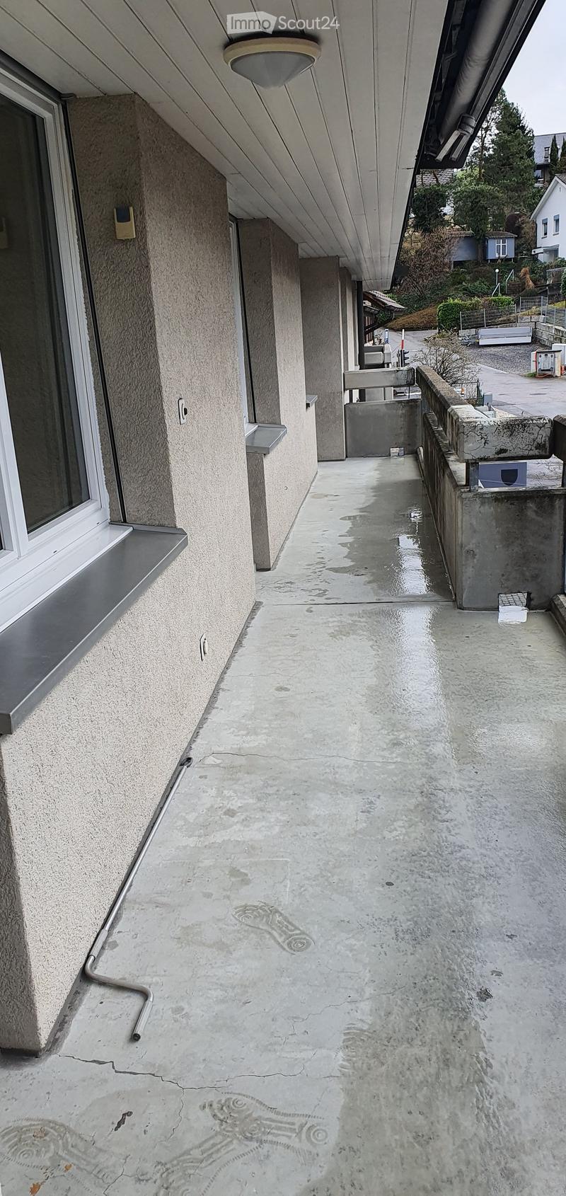 Balcony with concrete floor, metal railing, and a window with white frame