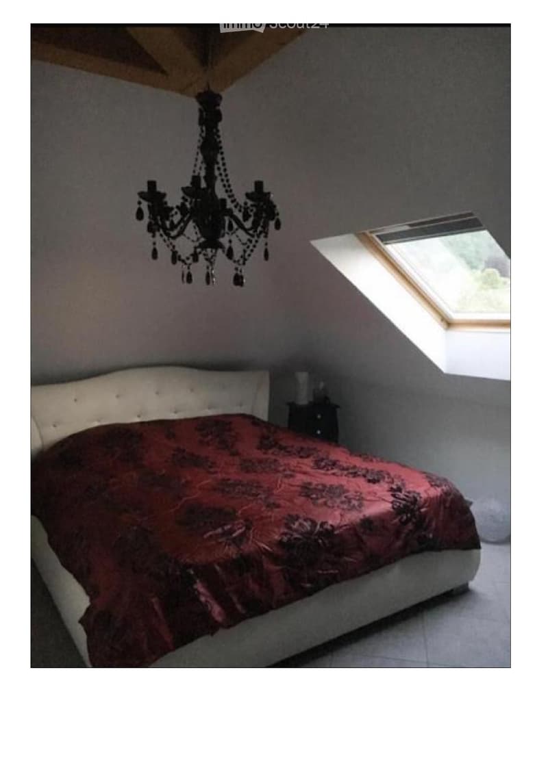 Bedroom with bed, chandelier, side table, white wall, grey floor, skylight, view outside