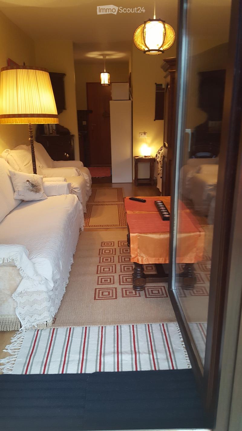 living room with sofa, lamp, coffee table, rug, side table, and a door leading to another room
