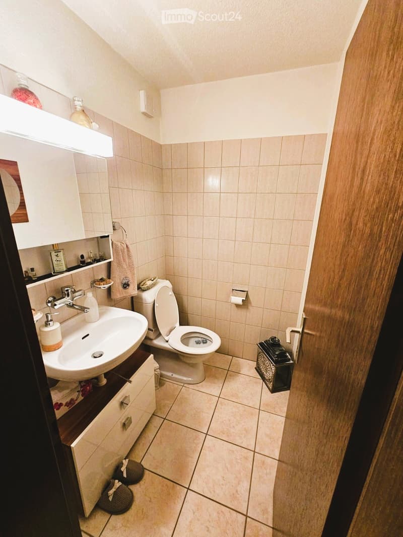 small bathroom with toilet, sink, mirror, and cabinet